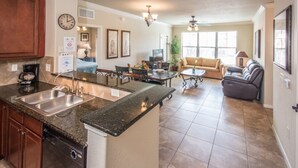 A spacious kitchen with granite countertops, a dining area with a sofa and coffee table, and a living room with a fireplace. - Bella Piazza 904 - 526 (Davenport)