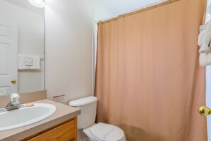 A bathroom with a sink, mirror, toilet, and shower curtain. - Hillcrest Estate 532 (Davenport)