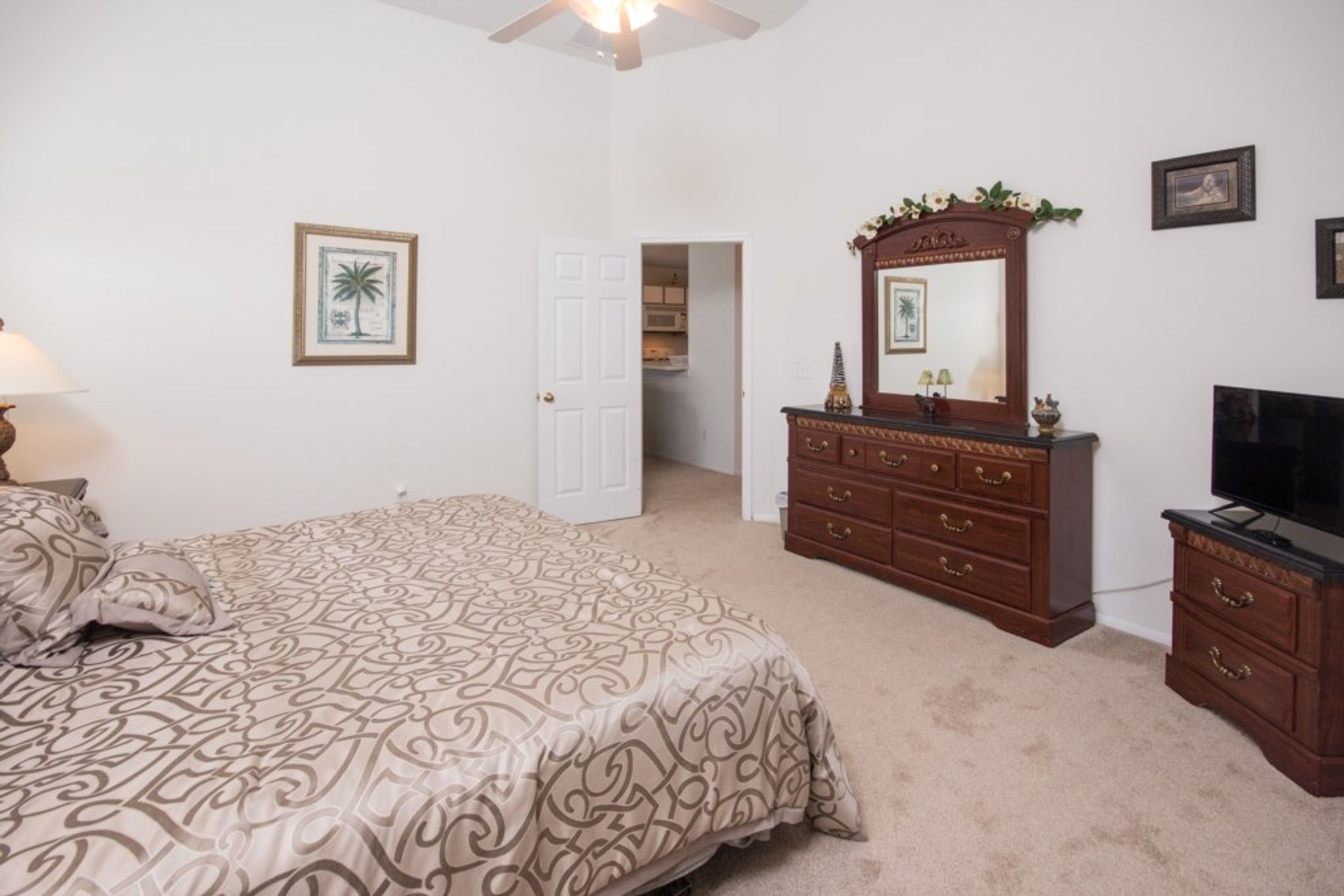 A bedroom with a bed, dresser, television, and a door leading to a closet.