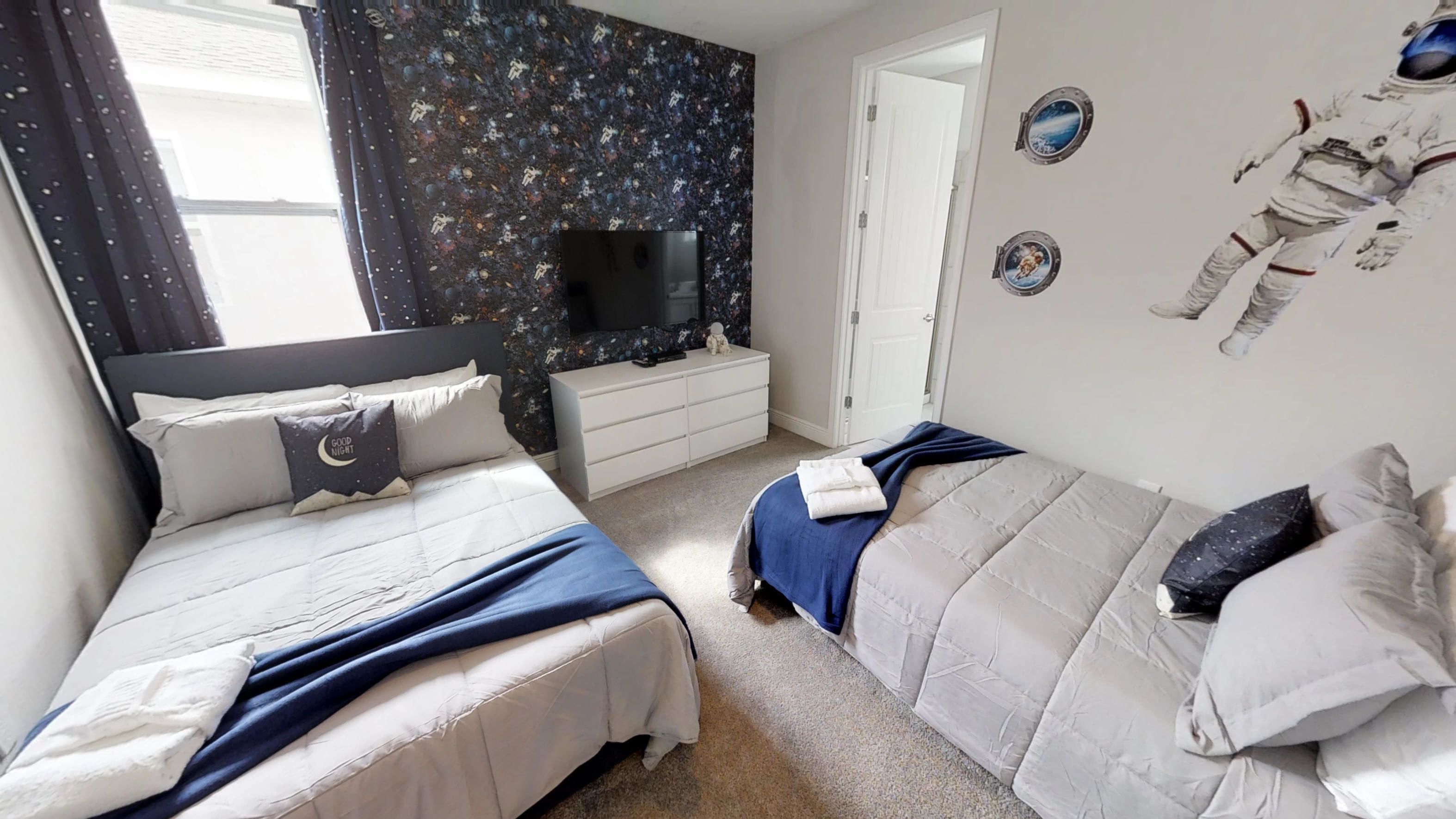 Una camera da letto con due letti, una televisione e decorazioni a tema spaziale.