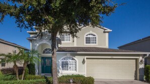 A two-story house with a garage, a front porch, and a tree in the front yard.