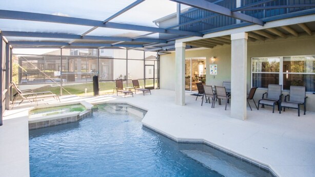 A covered outdoor swimming pool with lounge chairs and a patio area.