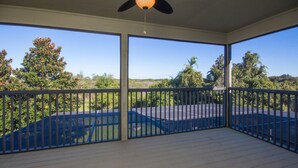 A covered outdoor area with a view of a tennis court and surrounding trees.