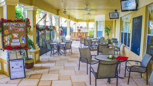 A covered patio area with outdoor seating, a sign for Caribbean Night Live Music, and a view of the outdoor space. - Windsor Hills 2591 (Kissimmee)