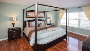 A four-poster bed with a dark frame, two bedside tables with lamps, and a window with curtains. - Windsor Hills 2591 (Kissimmee)