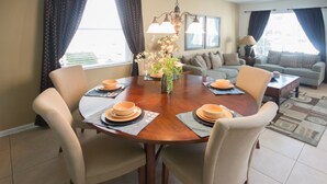 A dining area with a round table, six chairs, and a vase of flowers. - Windsor Hills 2591 (Kissimmee)