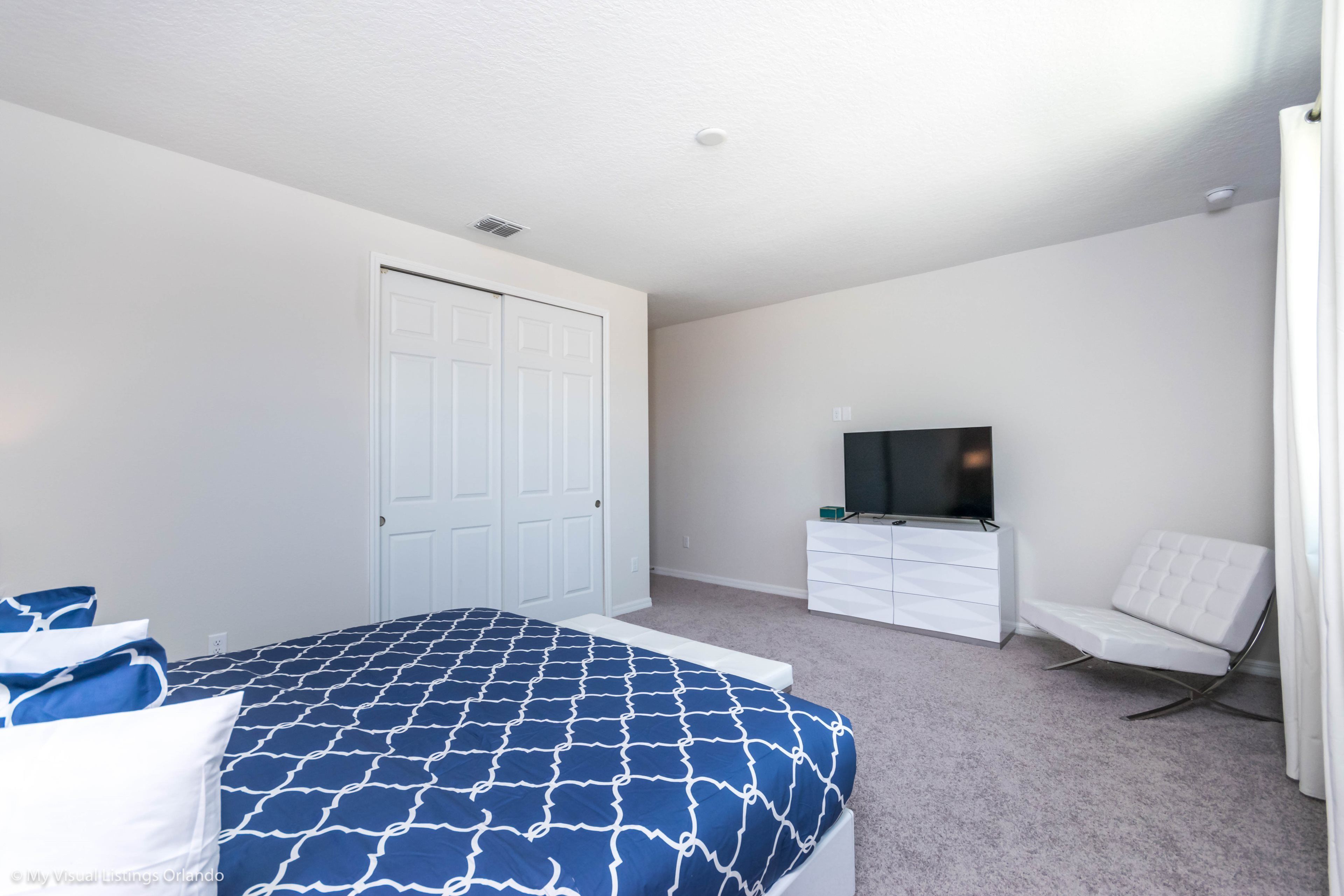 A bedroom with a bed, a TV, a dresser, and a chair.