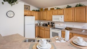 A kitchen with wooden cabinets, a refrigerator, a microwave, a stove, and a sink. - High Gate Park 204 (Davenport)