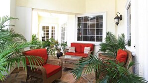 A sunlit patio with wicker furniture, a red sofa, and potted plants. - Legacy Dunes 8910 B16.208 (Kissimmee)