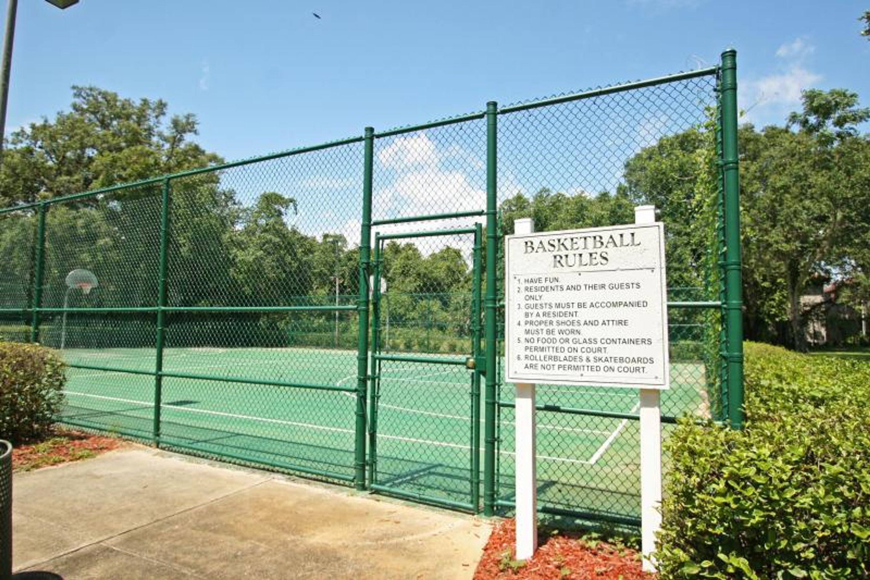 A basketball court with a sign listing rules.