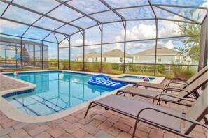 A covered outdoor swimming pool with lounge chairs and a hot tub. - Champions Gate 9033 (Davenport)