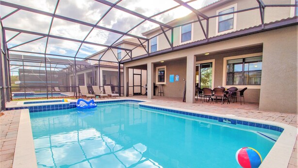 A covered swimming pool with lounge chairs and a beach ball. - Champions Gate 9033 (Davenport)