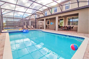 A covered swimming pool with lounge chairs and a beach ball. - Champions Gate 9033 (Davenport)