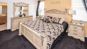 A bedroom with a large bed, two bedside tables, a dresser, a mirror, and a wall with a motivational quote. - Highlands Reserve Golf & Country Club 542 (Davenport)