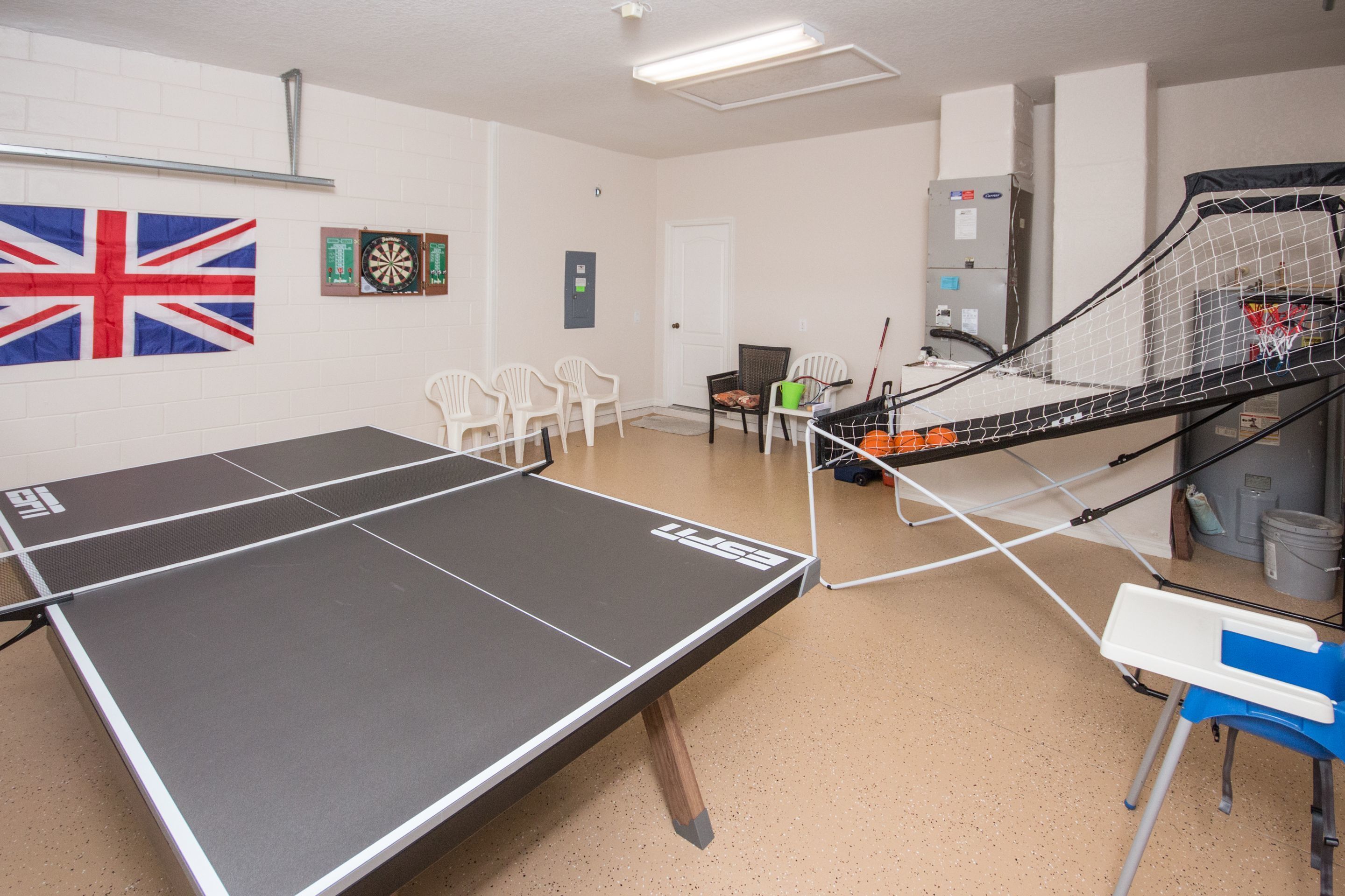 Ein Tischtennistisch in einem Raum mit weißen Wänden, einem Dartboard und einer britischen Flagge.