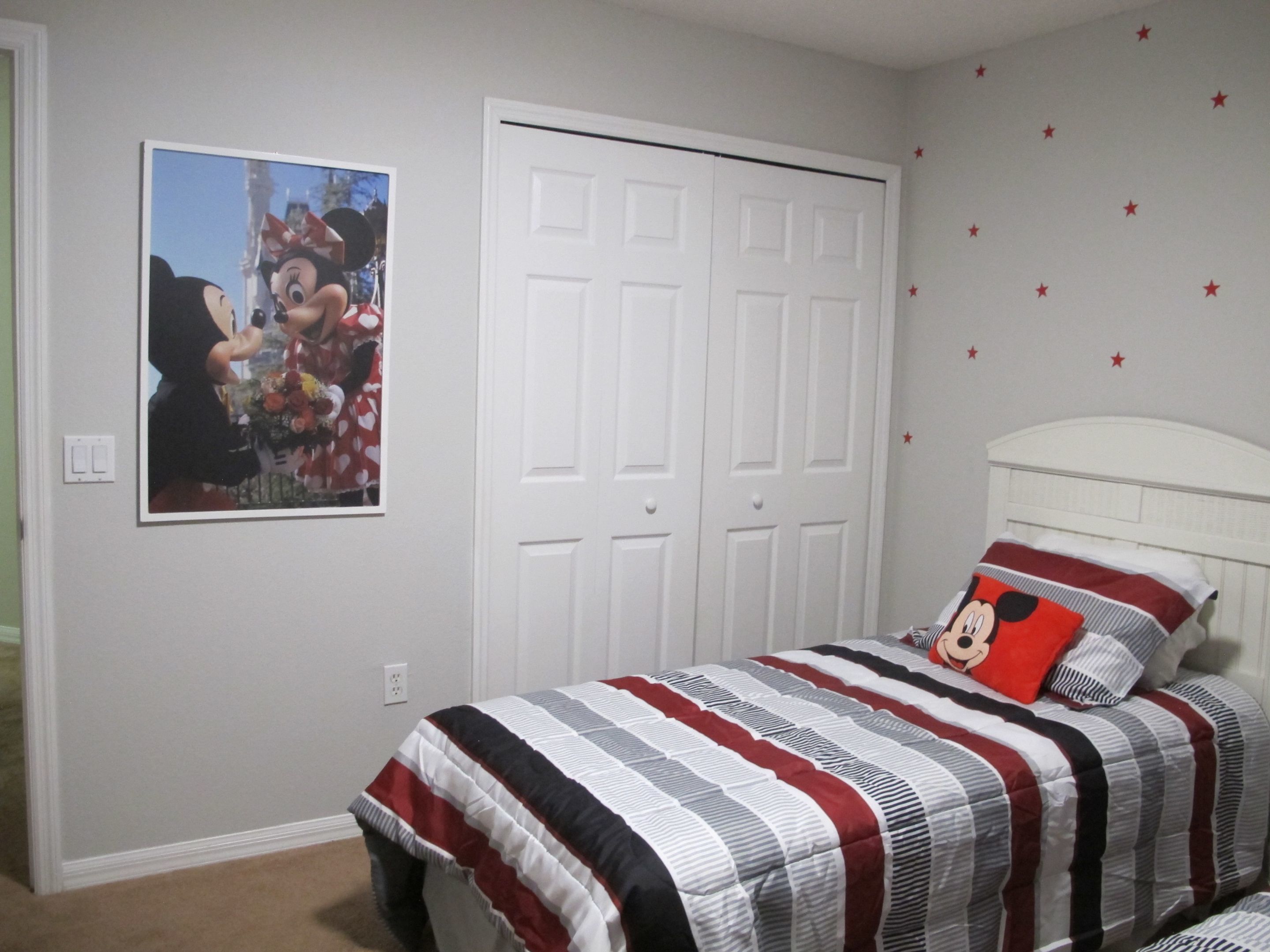 Un dormitorio con cama, una puerta blanca y una pared decorada con estrellas.