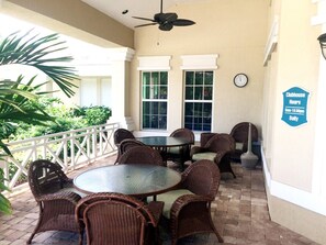 A covered patio area with wicker furniture, a ceiling fan, and a clock on the wall. - Windsor Palms 2301 - 203 (Kissimmee)
