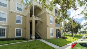 A beige multi-story building with a sign reading "2301 Butterfly Palm Way". - Windsor Palms 2301 - 203 (Kissimmee)