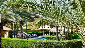 Un resort con piscina, palmeras y un edificio de techo con tejas.