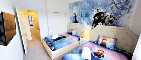 Une chambre avec deux lits, une fresque représentant un paysage hivernal et un téléviseur fixé au mur.