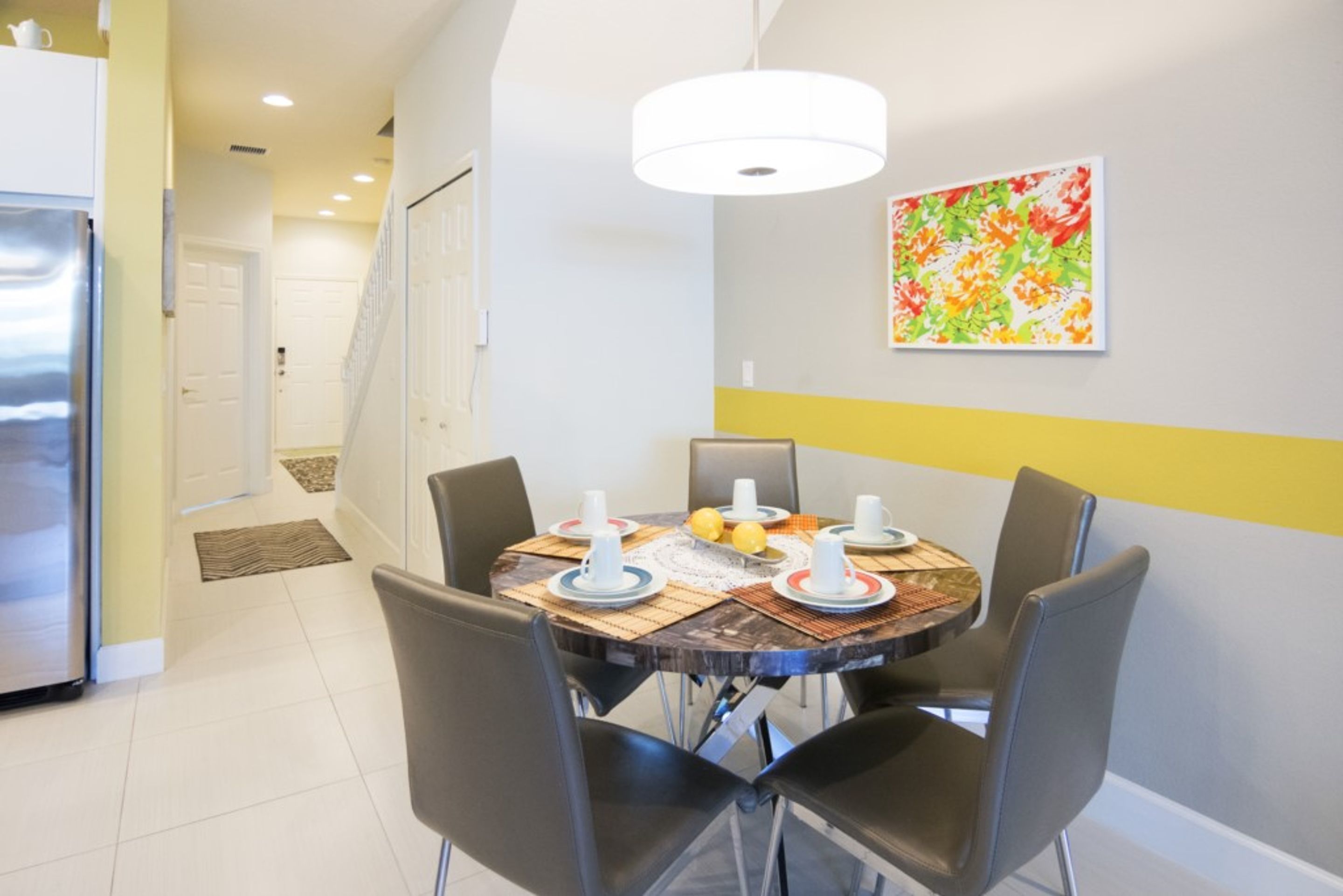 Un comedor con una mesa redonda, cuatro sillas y una lámpara colgante moderna.