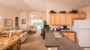Una cocina moderna con encimeras de granito, armarios de madera y un refrigerador blanco.