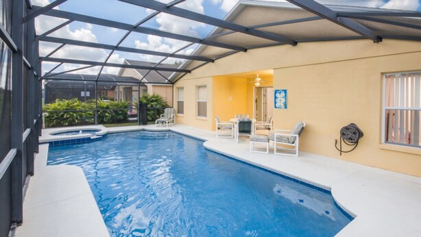 Una piscina interior con techo de vidrio, rodeada de sillones de descanso y una mesita.