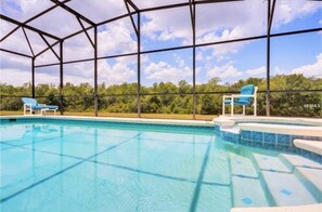 A swimming pool with clear blue water, surrounded by a metal frame structure, and two blue lounge chairs. - Legacy Park 454 (Davenport)