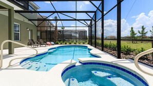 A swimming pool with a glass enclosure, surrounded by lounge chairs and a patio area.