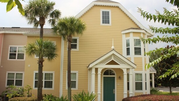 A two-story building with a green door and a small porch.