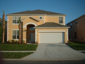 A two-story house with a garage, a front entrance with an arch, and a driveway leading to the garage.