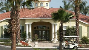 A hotel with a red-tiled roof, a central entrance with columns, and palm trees in the foreground. - Emerald Island Resort 8622 (Kissimmee)