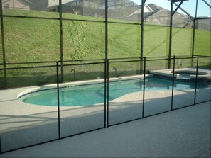 A swimming pool with a curved design, surrounded by a glass enclosure.