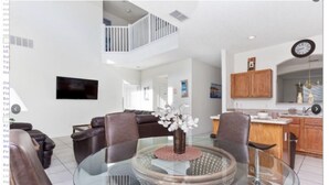 A modern living room with a glass coffee table, leather sofas, and a TV mounted on the wall. - Emerald Island Resort 8622 (Kissimmee)