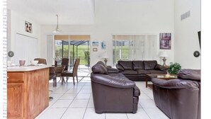 A spacious living area with a large sectional sofa, a dining table with chairs, and a kitchen area with a bar. - Emerald Island Resort 8622 (Kissimmee)