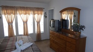 A bedroom with a bed, a dresser, a television, and a mirror. - Windsor Hills 7677 (Kissimmee)