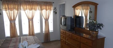 A bedroom with a bed, a dresser, a television, and a mirror.