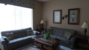 A living room with two sofas, a coffee table, and two lamps. - Windsor Hills 7677 (Kissimmee)
