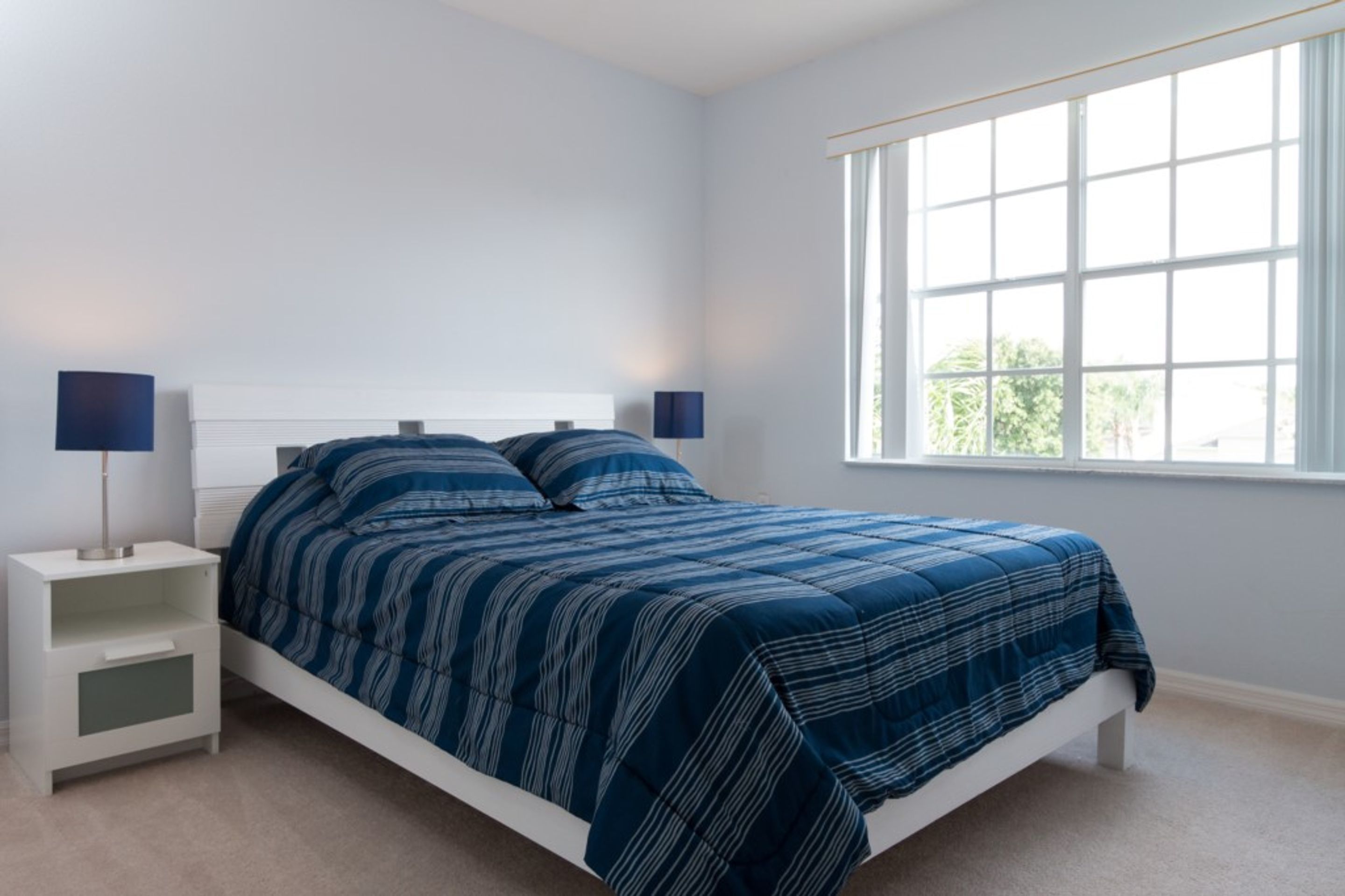 Une chambre à coucher avec un lit, des tables de chevet et une fenêtre.