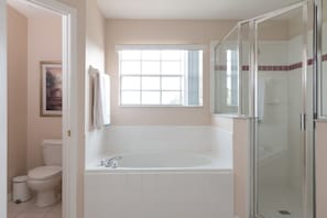 A bathroom with a bathtub, toilet, and shower area. - Cumbrian Lakes 4826 (Kissimmee)