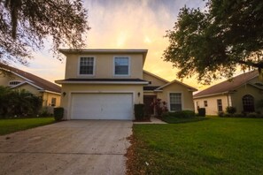 A two-story house with a garage, surrounded by a well-maintained lawn and trees. - Pinewood Country Estates 714 (Davenport)
