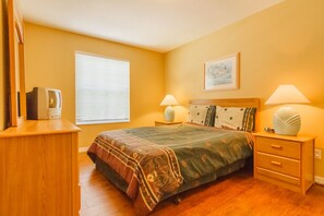A bedroom with a bed, bedside tables, a lamp, a picture on the wall, and a window. - Pinewood Country Estates 714 (Davenport)