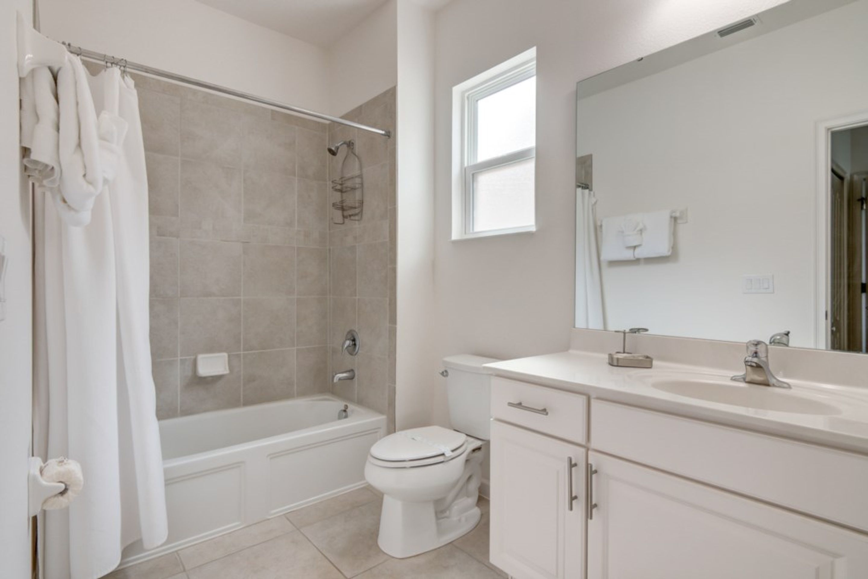 A modern bathroom with a bathtub, toilet, and vanity.