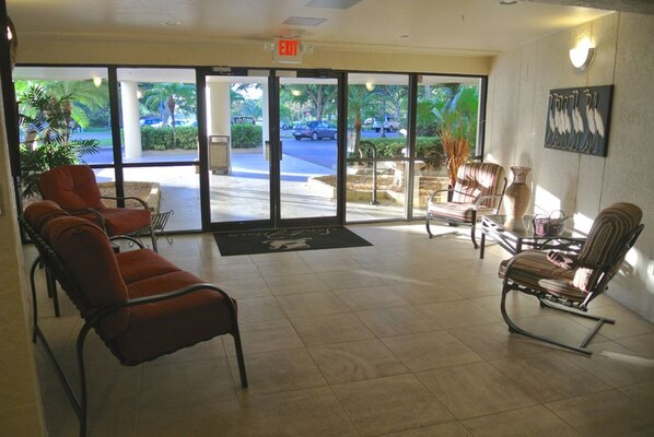 A lobby with a reception desk, seating area, and large glass doors leading outside.
