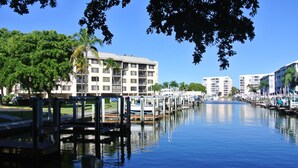 A marina with boats docked, a building with multiple floors, and a clear blue sky.