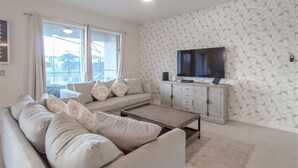 A modern living room with a sofa, coffee table, and TV. - Golden Palms Vacation Resort 2580 (Kissimmee)