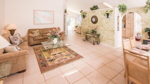 A spacious living room with a sofa, coffee table, and decorative plants. - Lindfields 2952 (Kissimmee)