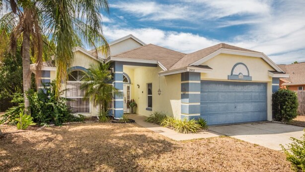 A single-story house with a blue garage, a small porch, and a well-maintained lawn. - Lindfields 2952 (Kissimmee)