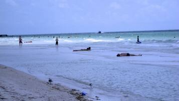 A beach with people swimming and walking along the shore.