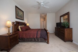 A bedroom with a bed, nightstands, a dresser, a ceiling fan, a mirror, and a plant. - Calabay Parc 215 (Davenport)